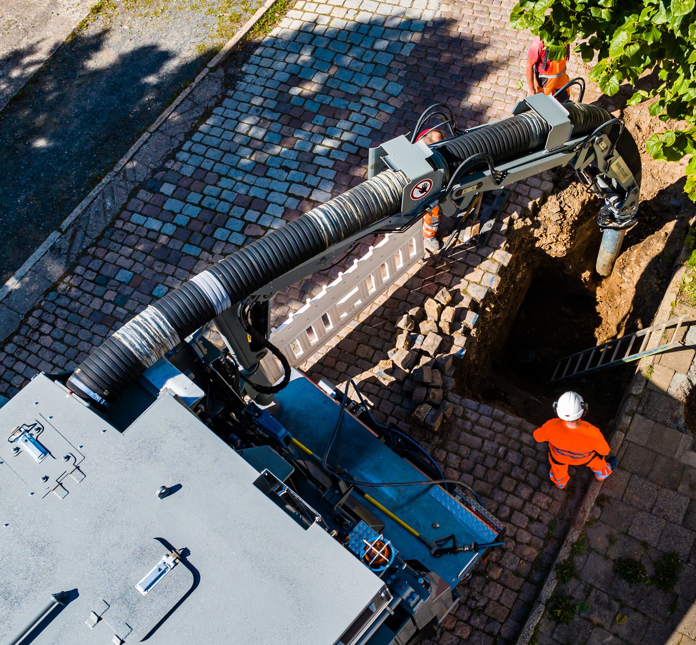 Suction excavation truck exposing a utility in an open trench